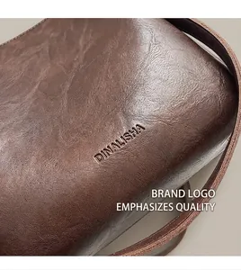 Detail shot of the embossed DINALISHA logo on dark brown leather texture of bucket bag