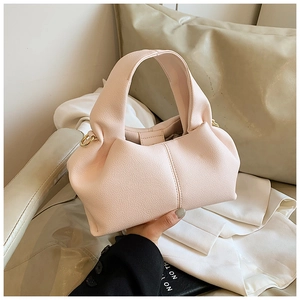Détail d'un sac à main en cuir rose clair avec texture litchi, design plissé et anneaux dorés
