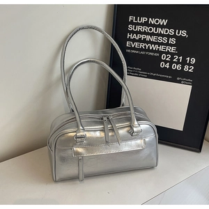 Detail of silver boston bag with pleated texture and dual zippers on marble surface