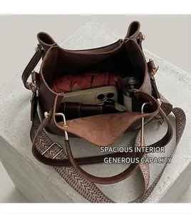 Detail view of large brown leather bucket bag interior with woven strap and metal hardware