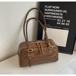 Detail view of the brown leather shoulder bag with dual zippers and long pulls
