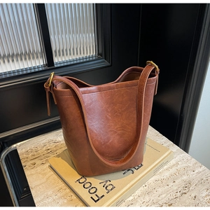 Detail of vintage brown water bucket bag in oiled PU leather with gold hardware