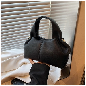 Gros plan sur le sac à main en cuir grainé noir avec anneau en métal doré et forme plissée