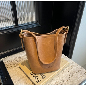 Detail of tan leather bucket bag with embossed logo on a vintage book setting