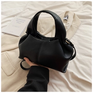 Détail de la texture cuir noir grainé sur sac à main avec crochets en métal doré
