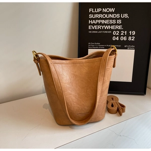 Close-up of retro brown PU leather bucket bag with golden hardware on marble surface