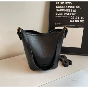Detailed shot of black bucket bag featuring metal ring buckle and premium pebbled leather