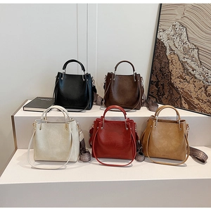 Detail view of five colored bucket bags with metal ring handles and retro patterned straps