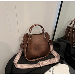 Close-up of dark brown bucket bag with lychee grain texture and golden metal handle