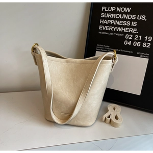 Detail of cream bucket bag showing vintage leather texture and gold metal ring hardware