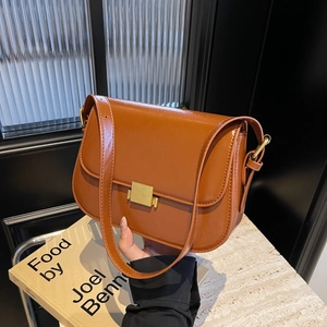 Brown faux leather shoulder bag with gold clasp shown in a lifestyle hand-held pose