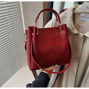 Detail of red bucket bag showing textured leather finish and gold metal hardware