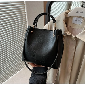 Detail of black lychee texture bucket bag with gold ring handle and embossed logo