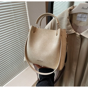 Detail of beige bucket bag with pleated leather texture and jacquard woven strap