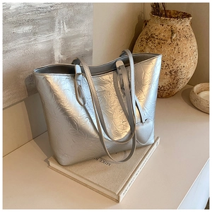 Detail of silver crinkled texture tote bag with heart pendant in an aesthetic setting