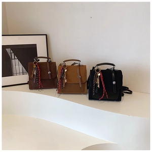 Close-up of vintage textured handbags in dark brown, camel, and black with metal handles