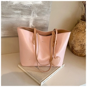 Close-up of pink tote bag featuring crinkled texture, slim straps, and heart charm
