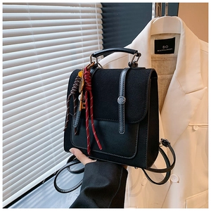 Detail of black leather and suede backpack with silver buckle and woven rope charm