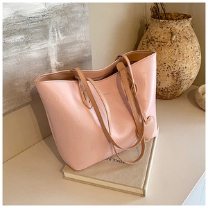 Detail of pink tote bag with textured leather, long straps and heart pendant charm