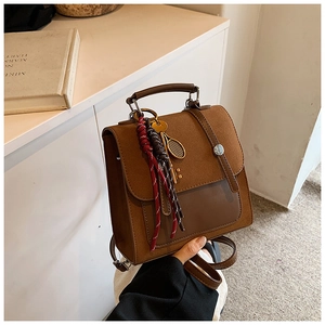Close-up of retro brown backpack with decorative woven rope and tennis racket charms