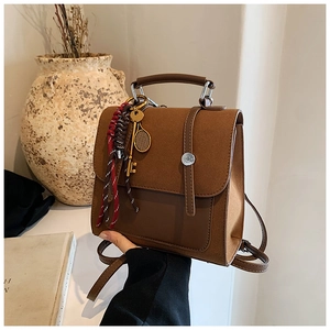 Close-up of brown suede backpack with vintage key charm and braided rope detail