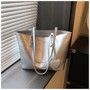 Detailed macro view of silver metallic crinkled tote bag with matching heart charm