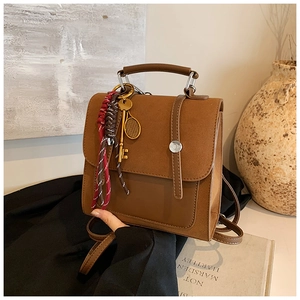Brown vintage leather backpack with metal ring handle and trendy decorative keychain details