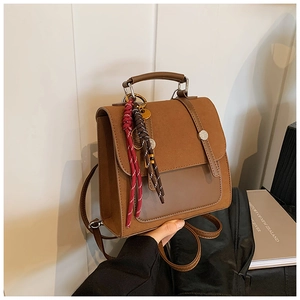 Detail of vintage brown leather backpack with frosted texture and braided charm