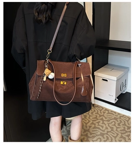 Close-up of brown suede tote bag with metal twist lock and unique baseball charm