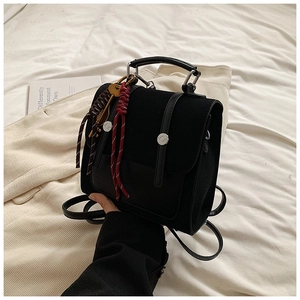 Close-up of black backpack featuring silver metallic buckles and colorful woven ornaments