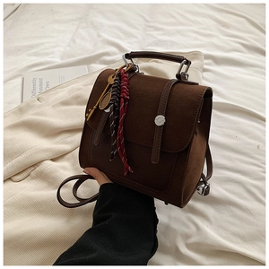 Close-up of vintage brown suede backpack with metallic buckles and stylish tassel detail