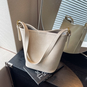 Minimalist creamy white leather bucket bag with gold hardware and adjustable strap