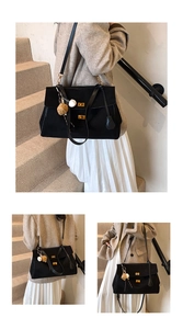 Detail of black tote bag with double gold turn-locks and decorative charm pendants