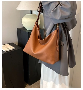 Detail of brown leather tote bag side buckle and pebbled texture for casual styling