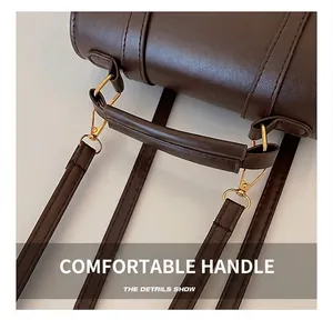Macro detail of dark brown leather handle and gold hardware on minimalist backpack