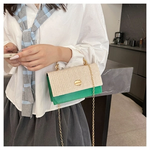 Détail d'un sac bandoulière en cuir vert et tissu tressé avec chaîne dorée et boucle métal