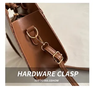 Macro shot of durable gold-tone metal hooks and fine stitching on a brown leather bag