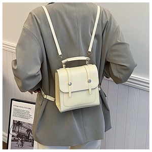 Detail of a beige mini backpack in faux leather with silver buckles and adjustable straps