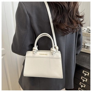 Detail of white mini square bag showing FASHION BAG embossing and knot handle style