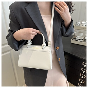 Detail of white rectangle bag with knot handle, gold hardware and fashion lettering