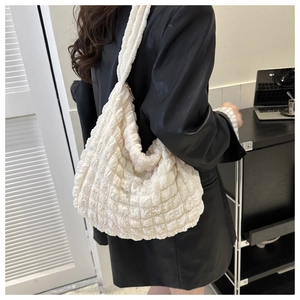 Detalle de bolso de hombro acolchado blanco con textura de burbuja y cremallera dorada