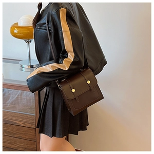 Detail of dark brown vintage faux leather crossbody bag with gold round metal buckles