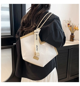 Detalle del bolso tote tejido de gran capacidad con cintas y elegantes correas en contraste