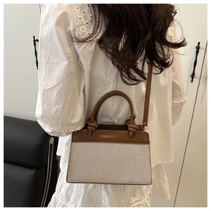 Detail of a brown leather and beige woven crossbody bag with dual-use handles