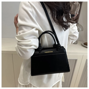 Lifestyle view of a black leather handbag with gold 'FASHION BAG' text and crossbody strap
