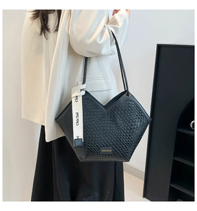 Detalle de bolso shopper negro trenzado con correa de logo y diseño de corte en V