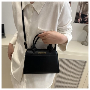 Detail of elegant black crossbody bag with gold text print and adjustable shoulder strap