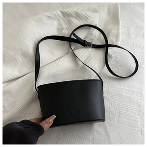 Close-up of the embossed logo on the black leather bucket bag with adjustable strap