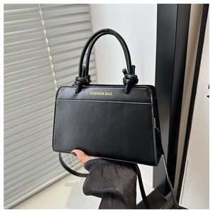 Detail of matte black handbag with knotted handle and gold Fashion Bag lettering