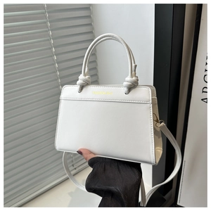 Detail of white saddle bag with knotted handle leather design and golden text